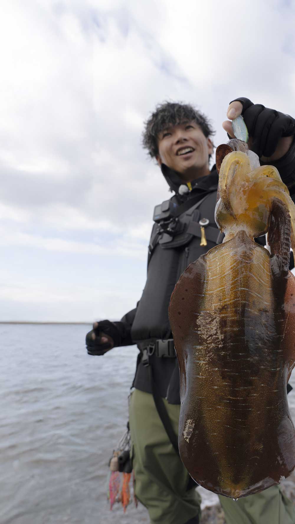 釣り上げたビッグサイズのアオリイカを掲げ、笑顔を見せる勝股