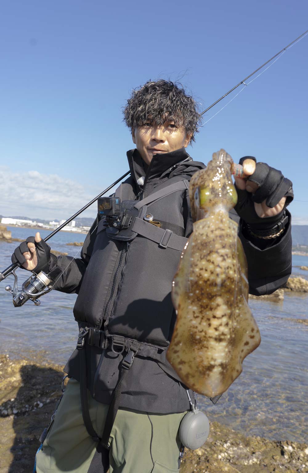 竿を右肩に掛け、左手でアオリイカを持つ勝股