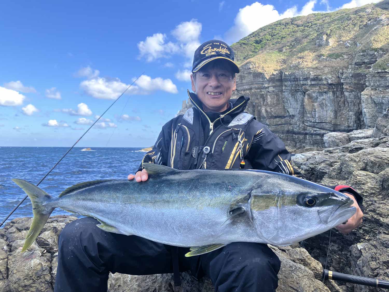 北村の両膝に乗せられた115cmのヒラマサ。釣り上げた北村は笑顔だ。