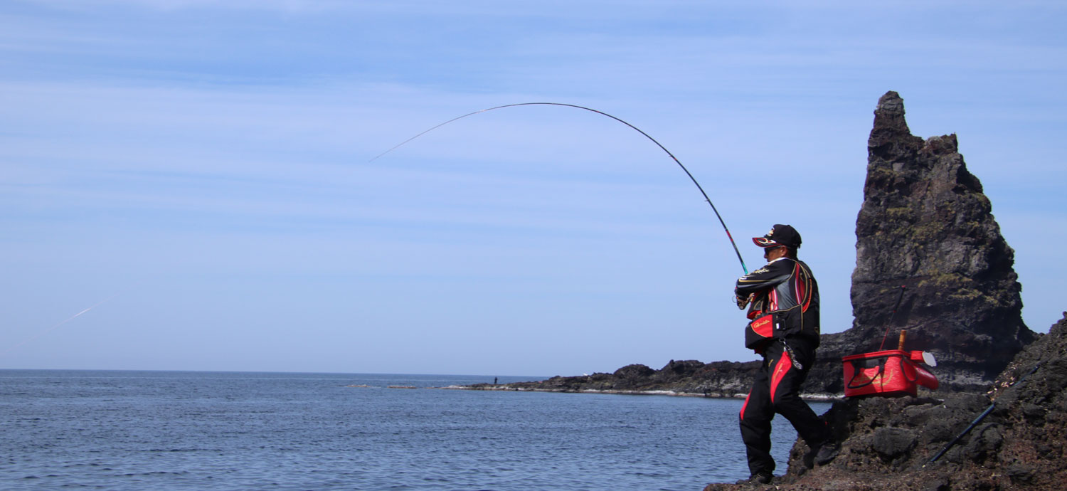 大きく竿を引き、魚とやり取りする南