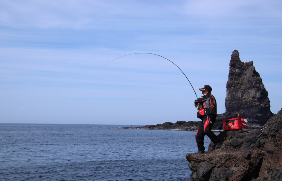 大きく竿を引き、魚とやり取りする南