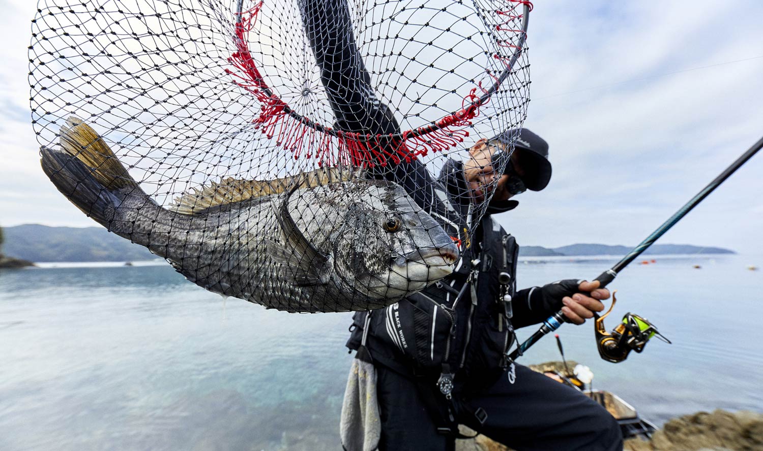 タモに収まったチヌを掲げる沖永