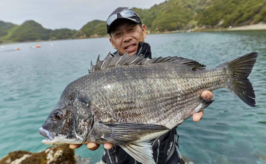 釣り上げたチヌを両手に持つ沖永