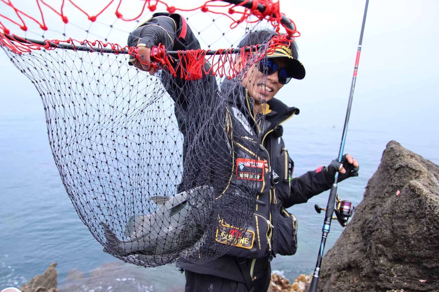 タモ網に収まった尾長グレを掲げる前岡インストラクター