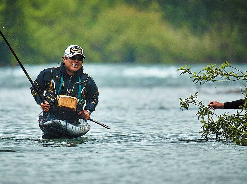 巨大サクラマスが収まった鮎ダモを手に、岸へと歩む長谷川