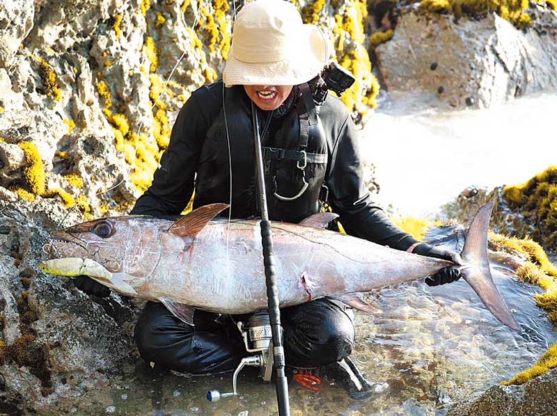 釣り上げた大魚を両膝に乗せているアングラー