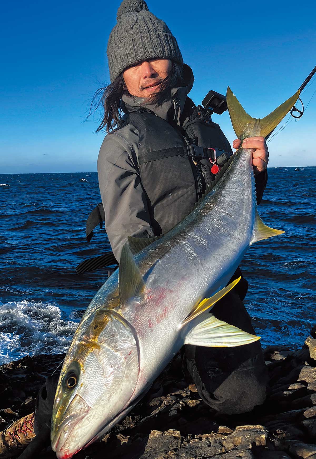 釣り上げた大魚を両手に持ち、掲げるアングラー