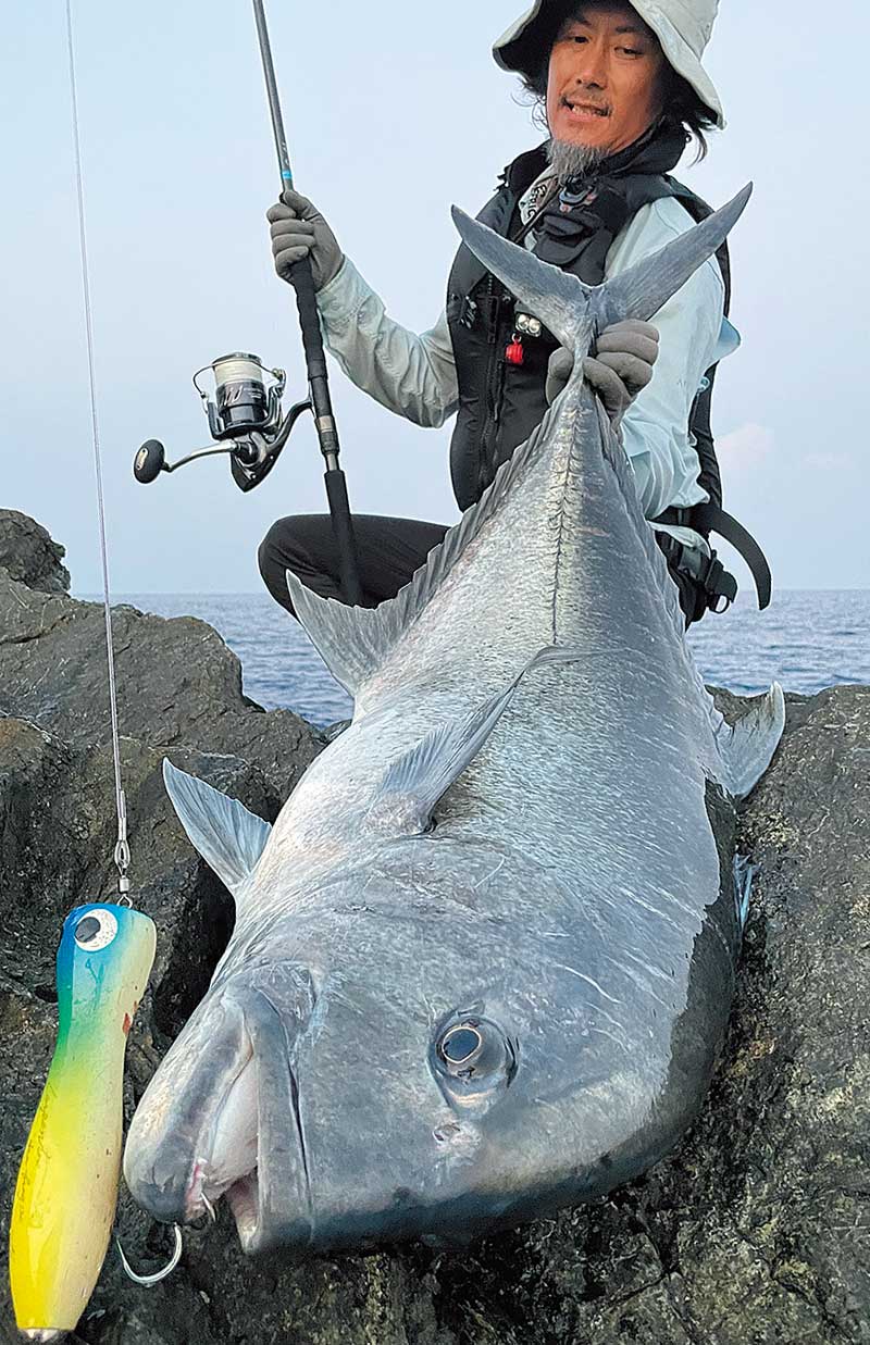 右手にアークフレックスRS、左手に釣り上げた大魚を持つアングラー