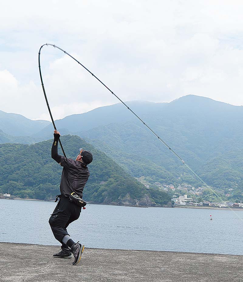 大きく振りかぶり、海へキャストするアングラーの写真