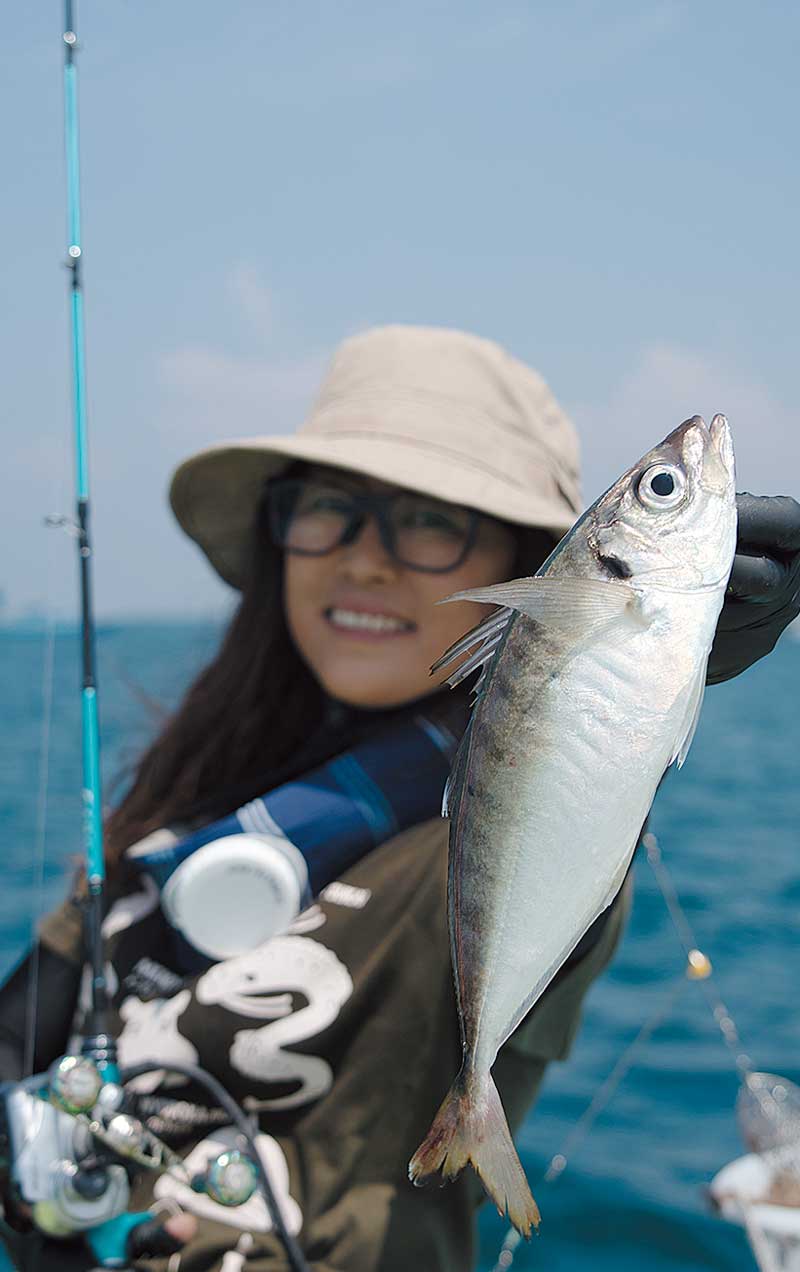 釣り上げた魚を掲げる三石