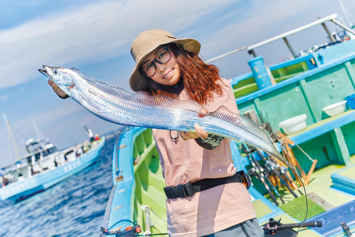 釣り上げたタチウオを両手に持ち、笑顔の三石