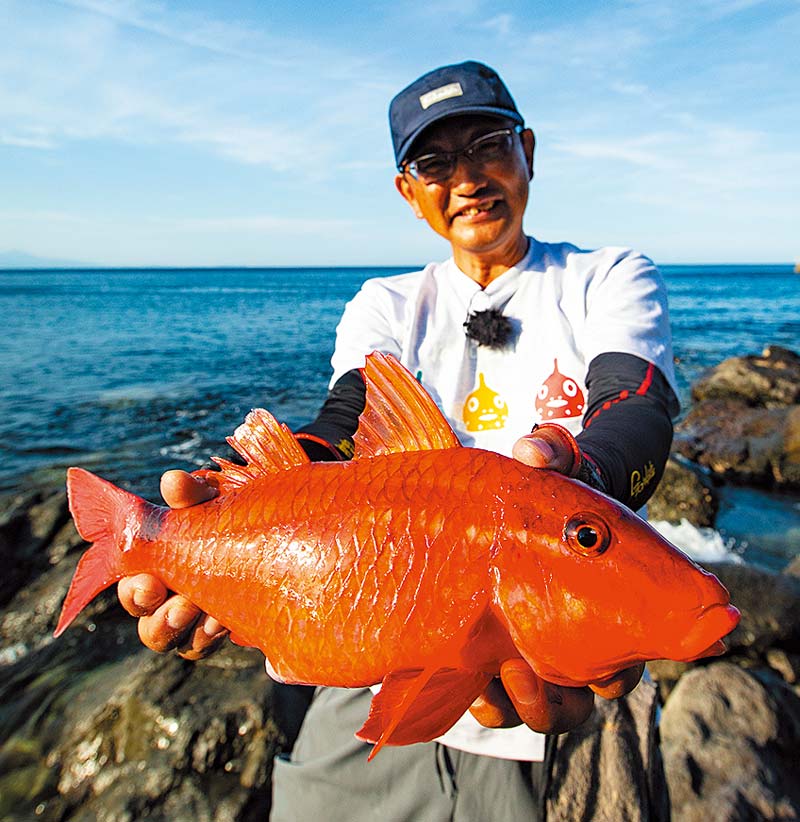 釣り上げたオジサンという魚を両手に持ち、笑顔の林