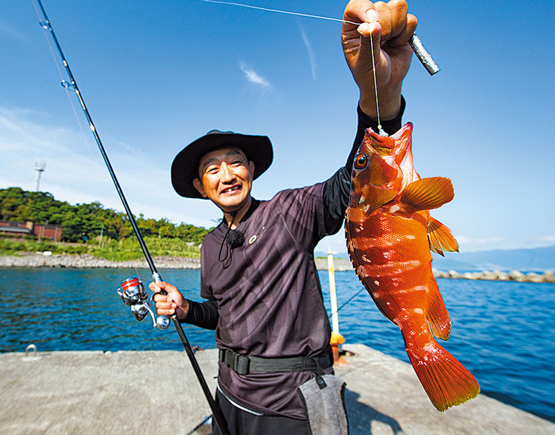 ラインを持ち、釣り上げたアカハタを掲げる林