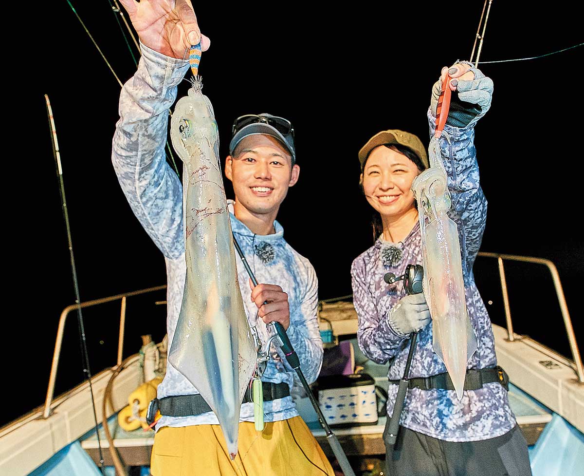 釣り上げたイカを掲げ、笑顔を浮かべる2人のアングラー